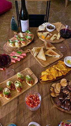 a wooden table topped with lots of food and wine glasses next to plates of food