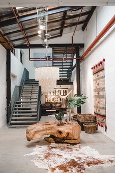 a living room filled with furniture and a wooden table in front of a stair case