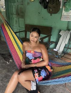 a woman sitting in a hammock with her legs crossed and looking at the camera