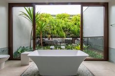 a large bathtub sitting in the middle of a bathroom next to a plant filled wall