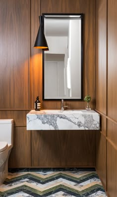 a bathroom with wood paneling and marble counter top, along with a white toilet