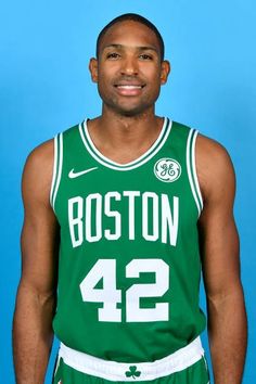 a man in a boston basketball uniform posing for a photo with his hands on his hips