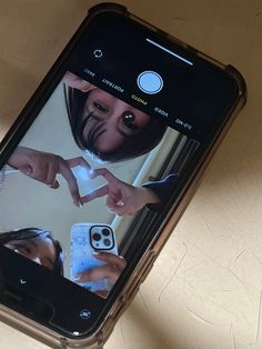 a person holding an iphone in their hand with the screen showing two people touching hands