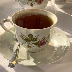 a cup of tea sitting on top of a saucer next to two cups with spoons