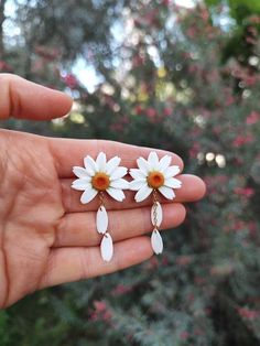 a person holding two white flowers in their hand