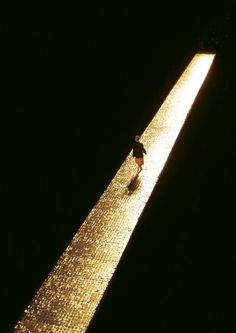 a person standing on the side of a tall building at night with their feet in the water