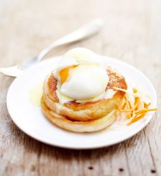 a white plate topped with pancakes covered in butter and syrup on top of a wooden table