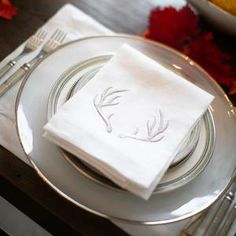 a place setting with white napkins and silverware