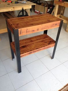 a wooden table sitting on top of a white tile floor next to a workbench