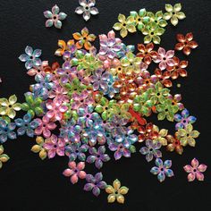 many different colored flowers on a black surface