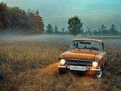 an orange car is driving through the foggy field