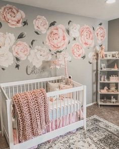 a baby's room decorated in pink and gray with roses on the wall, crib bedding, and rug