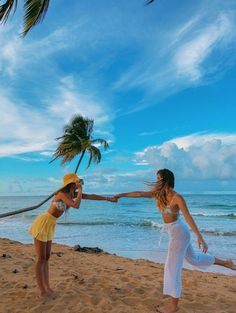 two women on the beach holding hands with palm trees in the background and blue sky