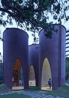 an unusual building with three arches and two people sitting on the bench in front of it