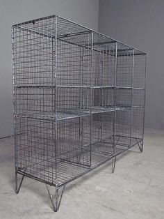 a large metal cage sitting on top of a white floor next to a wall with two doors