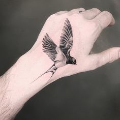 a person's hand with a bird tattoo on it