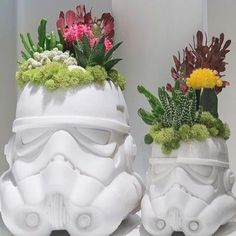 two planters with plants in them are shaped like stormtroopers and flowers