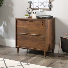 a wooden dresser sitting next to a chair in a room with a clock on the wall