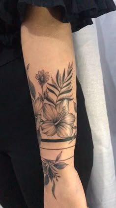 a woman's arm with flowers and leaves on the top half of her arm