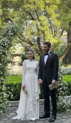 a man and woman in formal wear standing next to each other on a brick walkway