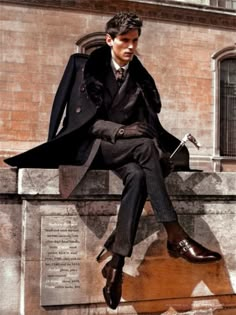 a man in a suit and tie sitting on a wall