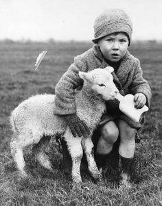 a young boy is sitting on top of a sheep and holding it's head