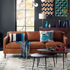 a living room with black walls and brown leather couches in front of large windows