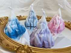 three soaps are sitting on a gold tray with white and blue fabric in the background