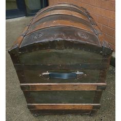 an old trunk is sitting outside on the ground next to a brick wall and door