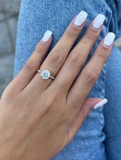 a woman's hand with white manicured nails and a ring on her finger