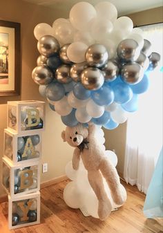 a teddy bear is on top of a bunch of balloons in the shape of letters