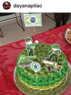 a cake with green icing and decorations on it sitting on a red tablecloth