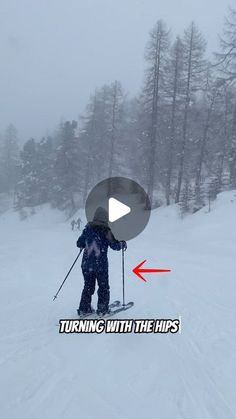 a person riding skis on top of a snow covered slope with trees in the background