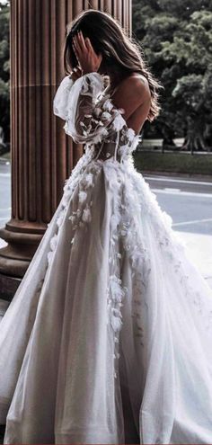 a woman in a white wedding dress standing next to an old pillar with columns behind her