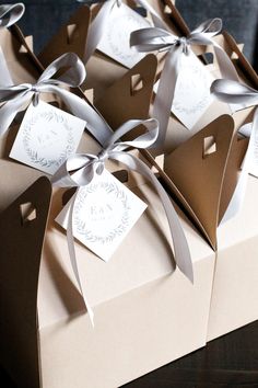 several brown boxes with white tags tied to each other and bows on the top one