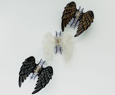 three black and white angel wings are attached to the back of an earpieces