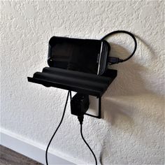 a cell phone hooked up to a charger attached to a wall with a cord