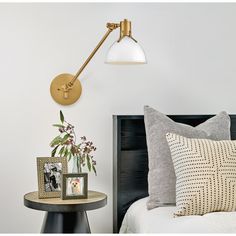 a bed room with a neatly made bed and a wall mounted light on the side