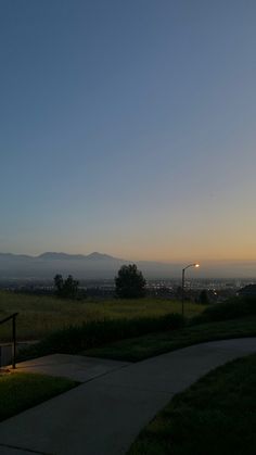 the sun is setting over an open field with mountains in the distance and grass on the ground