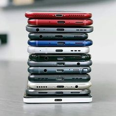 a stack of cell phones sitting on top of each other in front of a laptop computer