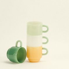 two green and yellow cups sitting next to each other on a white surface with no one around them