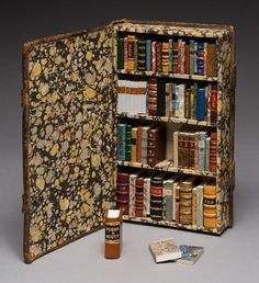 an open book case filled with lots of books next to a couple of small pieces of paper