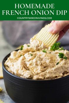 a hand dipping a cracker into a bowl of homemade french onion dip