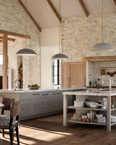 a large kitchen with an island in the middle and two pendant lights hanging from the ceiling