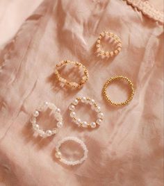 five pairs of pearled bracelets on top of a pink cloth