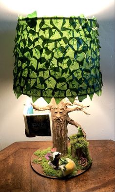 a lamp made out of paper and moss on a table with a book in front of it