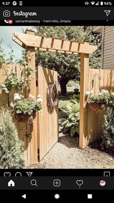 a wooden gate with two planters on each side and a wreath hanging from the top