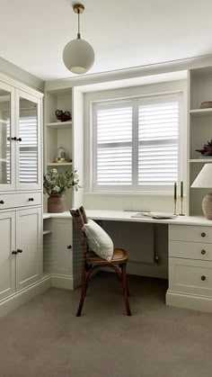 a chair sitting in front of a desk next to a window with shutters on it