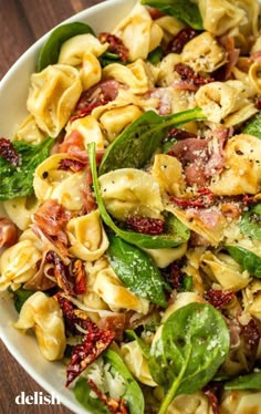 a white bowl filled with pasta salad on top of a wooden table next to a fork