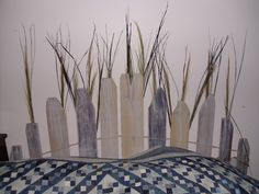 an arrangement of tall grass in vases on top of a table with blue and white checkered cloth